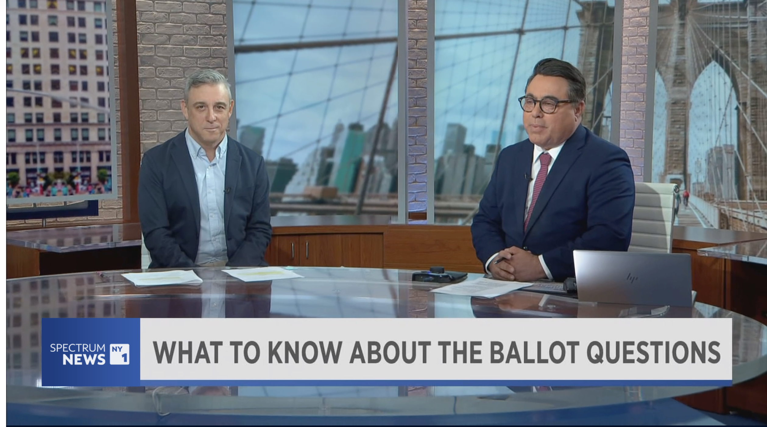 The NYC Votes Assistant Executive Director and NY1 sit at a news desk and discuss ballot proposals